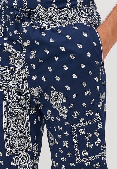 Tengerészkék nadrág fehér paisley mintákkal, különböző méretekkel és formákkal, puha anyagból készült, állítható derékpánttal és oldalzó zsebekkel.