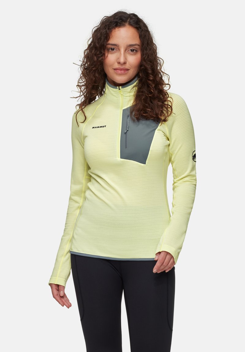 Langärmliges technisches Shirt in leuchtendem Gelb, mit einem grauen Brustpanel, Viertelreißverschluss und strukturiertem Stoff. Logo auf der linken Seite.