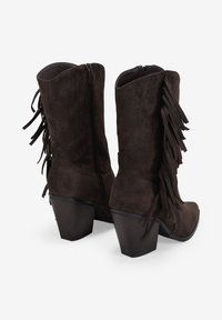 Botas de tobillo de ante marrón con tacón cuadrado, que presentan detalles de flecos a lo largo de los lados y un cierre de cremallera en la parte posterior.