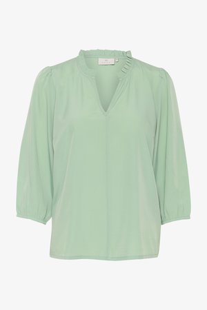 Lõtv mintroheline pluus V-kaelusega, volangkaeluse ja õhuliste varrukatega. Valmistatud kergest kangast. Sile tekstuur.