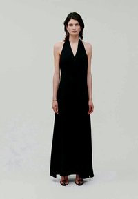 Vestido longo preto com alças halter e uma silhueta elegante, feito de tecido suave, apresentando um decote em V e um design minimalista.