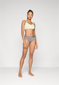 Ljusgrön bralette med tunna remmar, i kombination med grå hipsterunderkläder med logoband; slätt tyg och figursydd design.