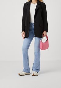 Černý oversized blazer, bílý žebrovaný top, světle modré zvonové džíny, bílé tenisky s šedými detaily a růžová kabelka s řetízkovým detailem.