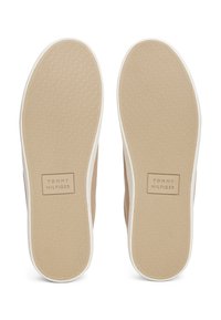 Béžové plátené tenisky s bielymi podrážkami. Štruktúrovaná gumová podrážka s logom Tommy Hilfiger. Jednoduchý dizajn a casual štýl.