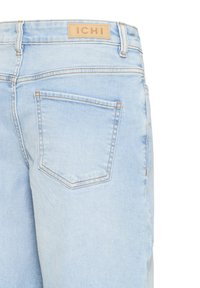 Jean en denim bleu clair vu de dos avec une seule poche visible et une étiquette de marque en cuir marron "ICHI" sur la ceinture.