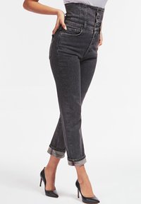 Jean en denim noir taille haute avec fermeture à bouton, cinq poches, ourlets retroussés et une légère élasticité pour le confort et l'ajustement.