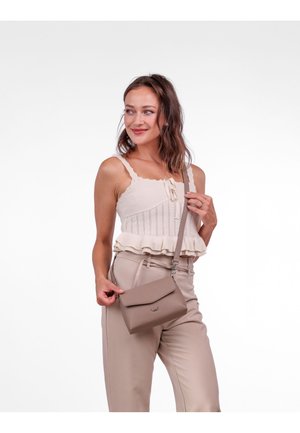 Béžová crossbody taška s klopou, texturovaným povrchem a logem. V kombinaci s pleteným topem a béžovými vysokými kalhotami.