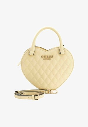 Sac à main en forme de cœur de couleur jaune clair, texture matelassée, garnitures en or, poignées supérieures et une bandoulière ajustable. Logo de la marque affiché.