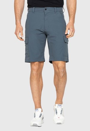 Pantaloncini cargo blu da uomo con tasche laterali indossati con sneakers bianche e una camicia nera, mostrati dalla vita ai piedi.
