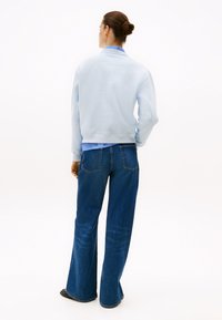 Ανοιχτό μπλε φούτερ με ριμπ μανίκια και γιακά, συνδυασμένο με σκούρο μπλε παντελόνι σε φαρδιά γραμμή, που διαθέτει πίσω τσέπες και ξεθωριασμένη υφή.