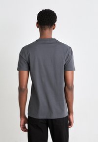 Grå bomulds t-shirt med korte ærmer og rund halsudskæring, der har en glat overflade og en lige pasform, set fra bagsiden.