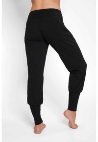 Schwarze Loungehosen mit hohem Bund, taillierten Knöchelbündchen und weichem, dehnbarem Material. Verfügt über dezente Falten auf der Rückseite.