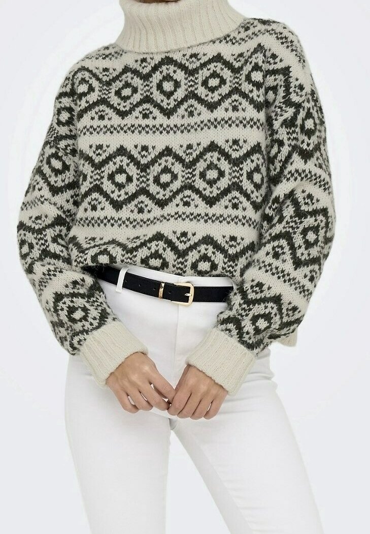 Pull à col roulé en maille crème avec motifs géométriques verts foncés ; poignets et ourlet côtelés ; coupe ample ; associé à une ceinture noire et un pantalon blanc.