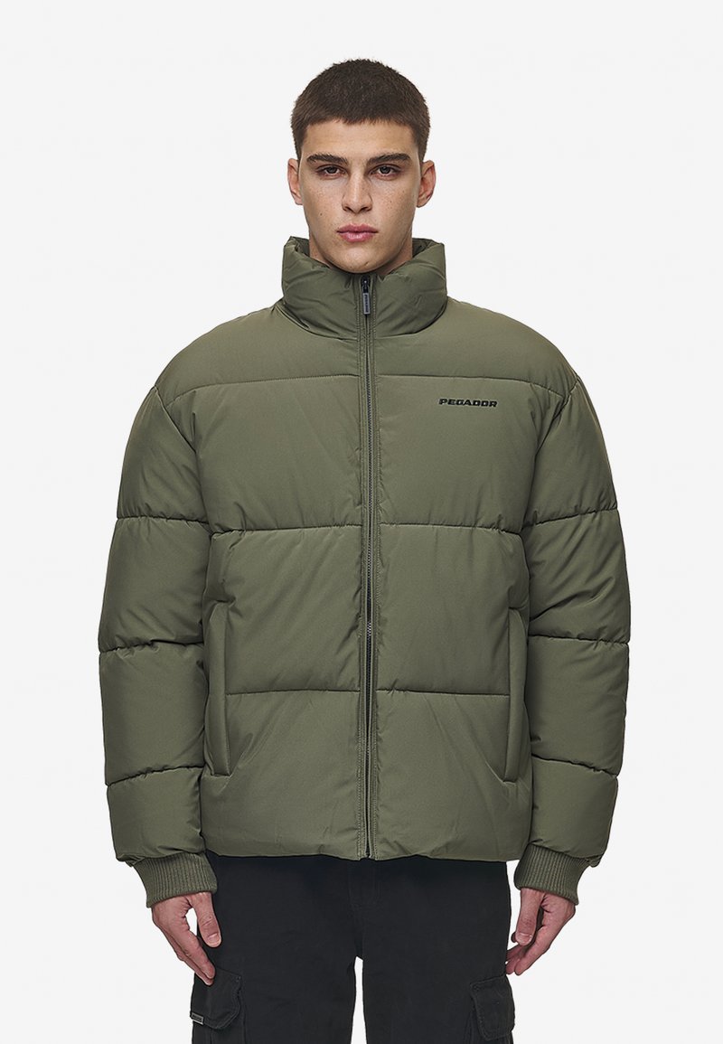 Jachetă puffer verde măsliniu cu guler înalt, fermoar frontal și design matlasat orizontal. Are manșete ribbate și un logo pe piept.