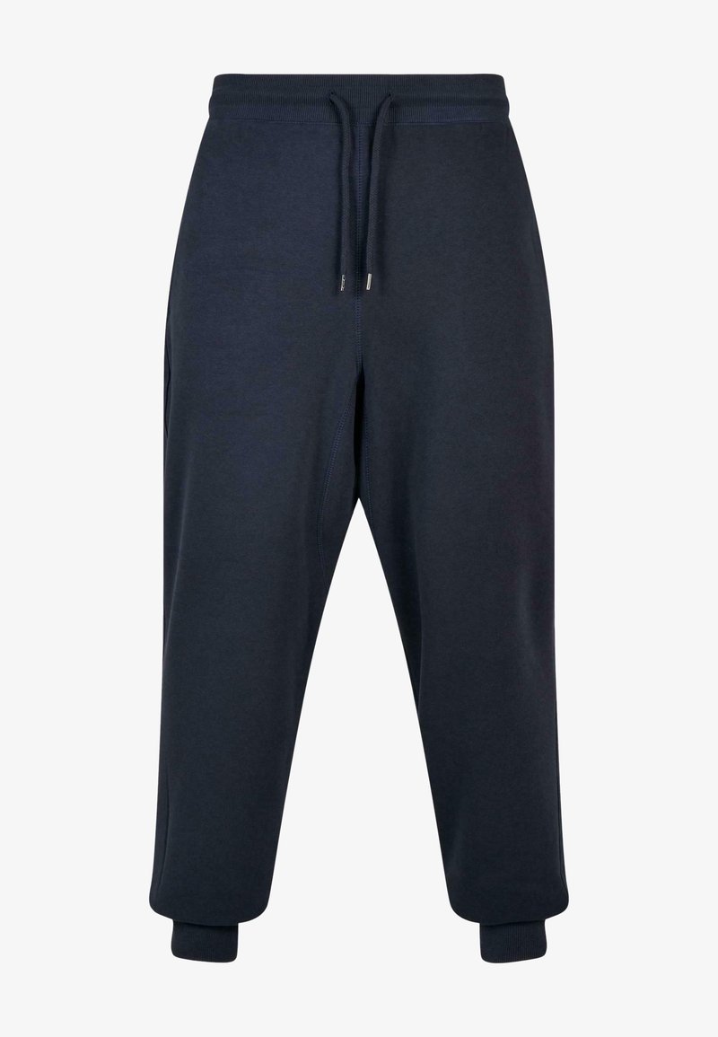Navy blue sweatpants in soft fabric, featuring an elastic waistband with adjustable drawstrings, side pockets, and tapered cuffs.