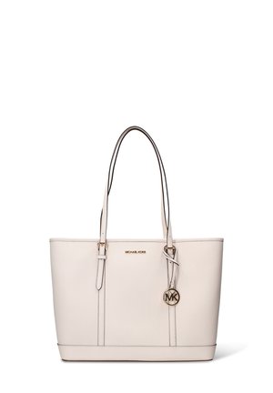 Sac fourre-tout en cuir beige avec deux poignées supérieures, logo doré et pendentif latéral. Texture lisse avec une silhouette structurée et des surpiqûres contrastées.