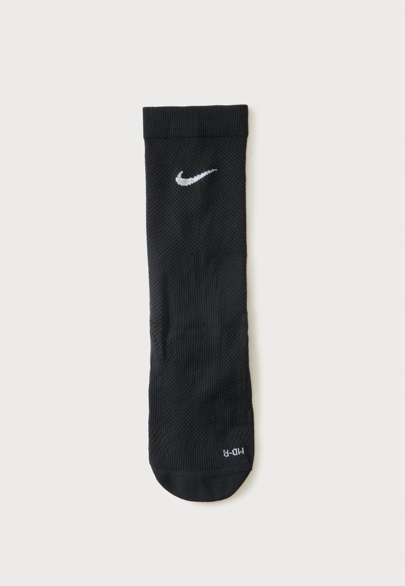 Μονή μαύρη αθλητική κάλτσα Nike με λευκό λογότυπο Swoosh κοντά στο μανσέτα, με ετικέτα "MD-R" στην περιοχή των δακτύλων, τοποθετημένη επίπεδα σε λευκό φόντο.