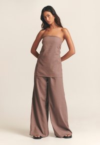 Bezramínkový taupe top spojený se širokými kalhotami taupe, vyrobený z texturované látky, s minimalistickým designem a uvolněným střihem.