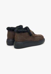 Brown suede ankle boots with black faux fur lining, featuring a thick black rubber sole and rounded toe. Side accent with lacing detail.