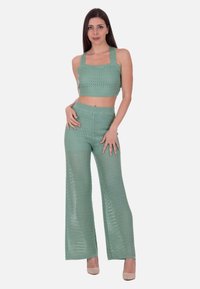 Mintgrøn to-delt outfit bestående af en cropped top med firkantet halsudskæring og brede bukser, begge i en perforeret strikstruktur.