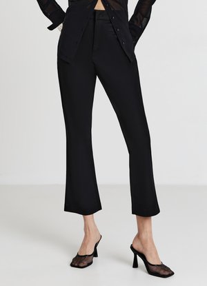 Pantaloni neri su misura con gamba dritta, caratterizzati da una texture liscia e un leggero lucido. Abbinati a décolleté slip-on in rete nera.