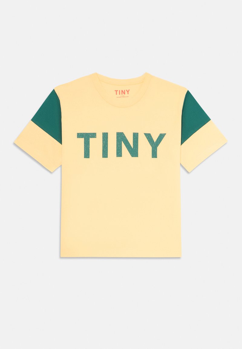 T-shirt gialla a maniche corte con accenti verdi sulle maniche. Presenta una scritta in rilievo "TINY" in verde. Collo rotondo.