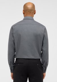 Grå mønstret skjorte med lange ærmer og knapmanchetter, der har en markant krave og glat stofstruktur.