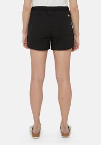 Pantaloni corti neri con cintura elastica, dotati di una tasca posteriore. Tessuto liscio, lunghezza sopra il ginocchio, design casual.