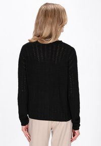 Zwarte gebreide trui met een gestructureerd, open patroon en lange mouwen. De achterkant heeft een geribde zoom en een klassieke ronde hals.