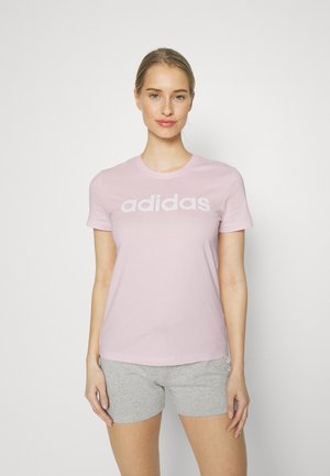 Camiseta de algodón rosa claro con el logo blanco de "adidas", de mangas cortas y corte relajado, combinada con pantalones cortos grises.