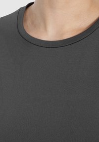 T-shirt grigia con scollatura rotonda, texture liscia e vestibilità aderente, che mette in risalto un design pulito e semplice.