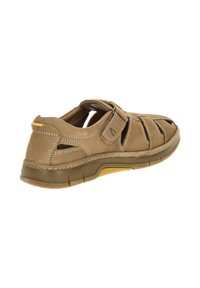 Light brown closed-toe leather sandal with adjustable strap, breathable cutouts, and rubber sole with yellow accents.