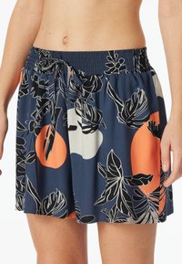 Námořnická modrá sukně s elastickým pasem, zdobená květinovým vzorem v černé a oranžové barvě. Lehká tkanina, uvolněný střih a detaily s tkaničkou.
