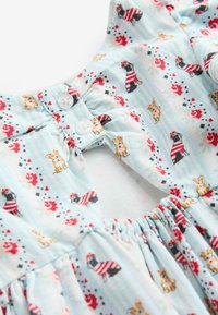 Robe en coton bleu avec un motif de petits chiens rayés et des accents floraux. Les détails comprennent des boutons et un tissu froncé au niveau du col.
