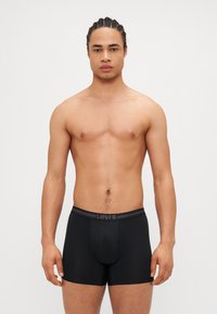 Fekete Levi's boxer alsónadrág puha derékkal. Az anyag sima, testhez álló, és minimalista dizájnnal rendelkezik, minta nélkül.
