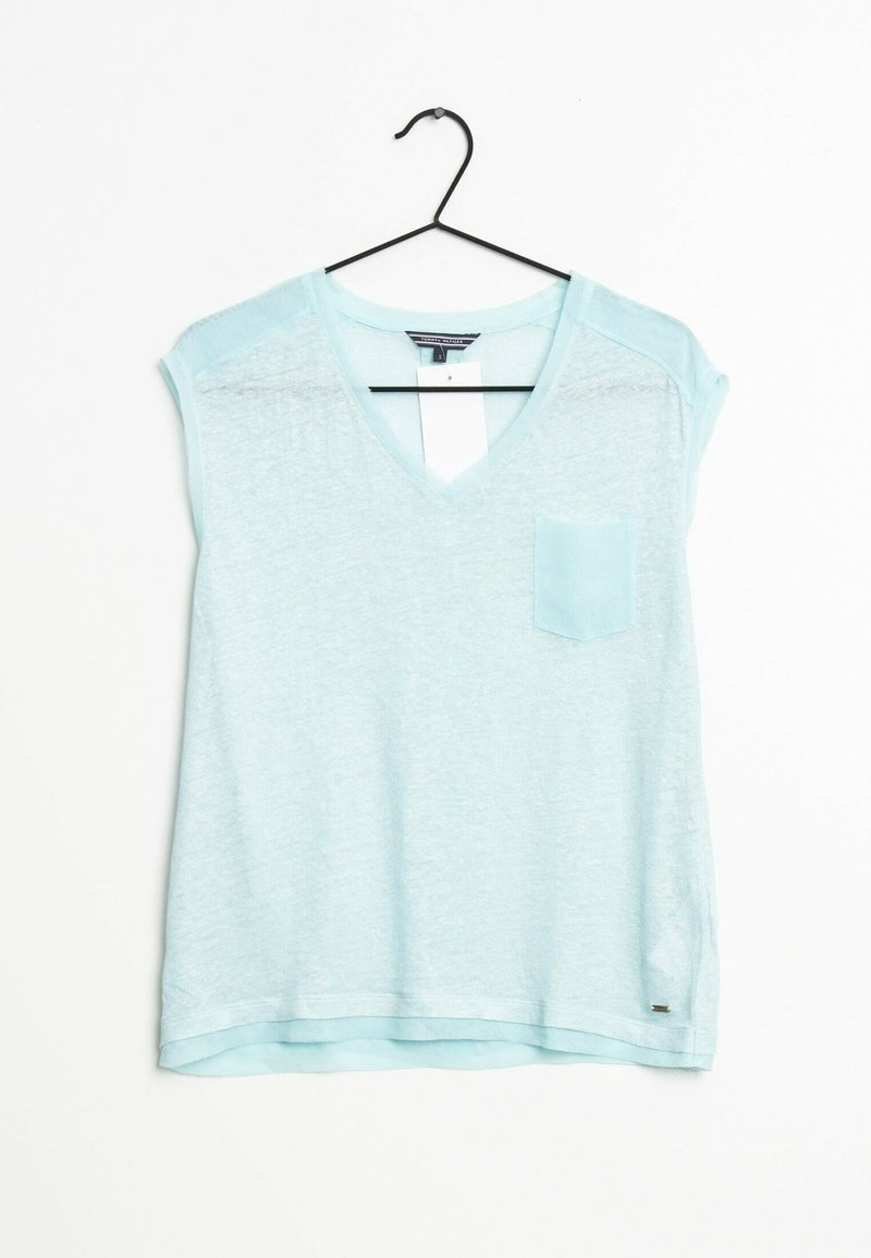 Top de manga corta en azul claro con escote en V, hecho de una tela suave y texturizada. Cuenta con un bolsillo en el pecho y un dobladillo curvado.