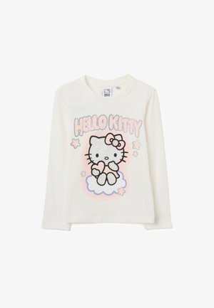 Langärmliges cremefarbenes Shirt mit einem glitzernden, gepunkteten Hello Kitty-Graphic, rosa Akzenten und Sternenmotiven auf einem hellblauen Wolkenhintergrund.