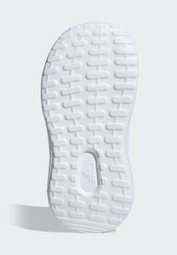 Biała podeszwa trampka z teksturowanej gumy, posiadająca małe prostokątne wzory dla lepszej przyczepności, gładkie krawędzie oraz owalne wcięcie z logo marki.