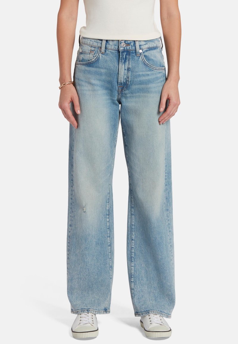 Jeans de mezclilla de pierna ancha en azul claro, con cintura alta, detalles desgastados y estilo tradicional de cinco bolsillos.