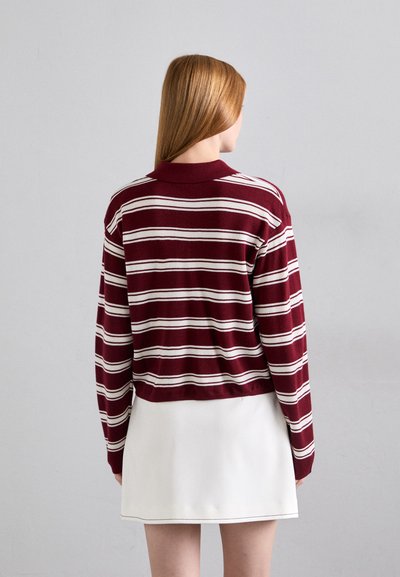 Bordeaux ja laitostriped pitkähihaisessa neulepaidassa on kaulus, lyhyt muotoilu, pehmeä rakenne, yhdistettynä valkoiseen minihameeseen.