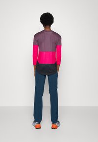 Langsleeve shirt met kleurblokken in roze, grijs en zwart; gepaard met blauwe broek; zachte stof; relaxte pasvorm.