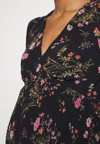 Abito nero con un motivo floreale in rosa e rosso. Presenta una scollatura a V, un tessuto texturizzato e arricciature in vita per un look aderente.
