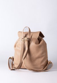 Tan leather backpack with a fold-over flap, adjustable straps, and gold-tone hardware. Soft texture and rounded shape for versatile use.