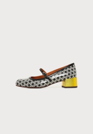 Zapato Mary Jane de mujer con patrón en blanco y negro, con correa negra y tacón ancho dorado brillante, mostrado de lado.