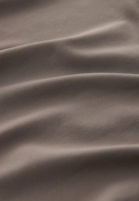 Blødt brunt stof med en glat tekstur, der har subtile bølger og stræk, og viser et ensartet design.