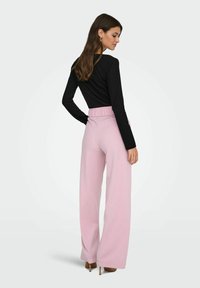 Black ribbed long-sleeve top paired with high-waisted, wide-leg pink trousers. Smooth fabric, relaxed fit, and elastic waistband.