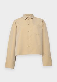 Cropped beige shirt made of cotton blend, featuring a pointed collar, button front, and a small chest pocket with logo embroidery.