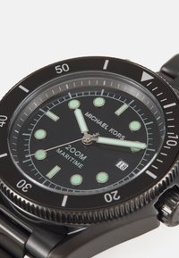 Reloj de acero inoxidable negro con caja redonda, marcadores de hora luminiscentes y un bisel giratorio marcado del 10 al 50 para fines de buceo.
