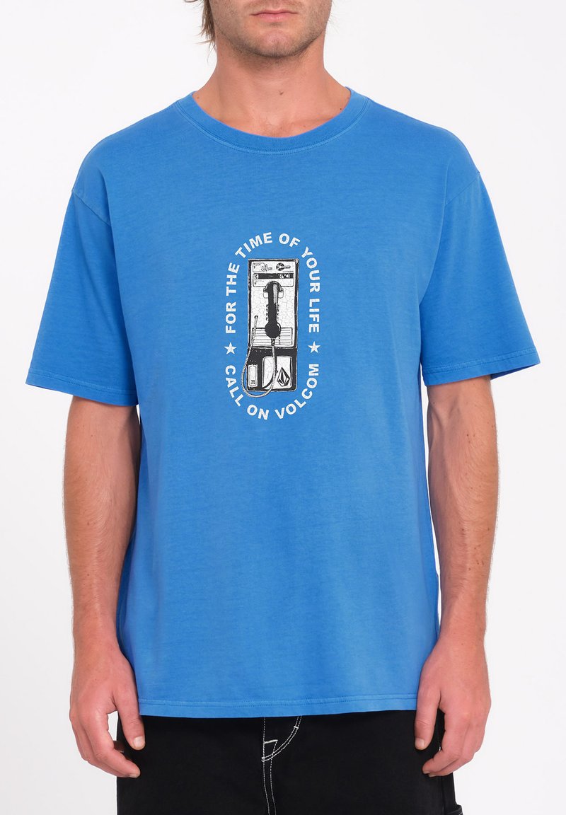 Blå bomulds t-shirt med et centralt grafik af en betalingstelefon og tekst. Korte ærmer, rund hals, afslappet pasform, glat tekstur.