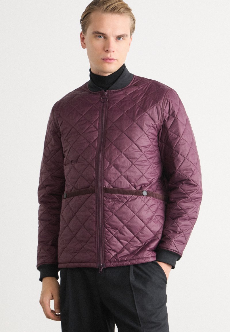 Quilted purple jacket with a zip front, featuring a high collar, side snaps, and black trim. Smooth texture with a diamond pattern design.